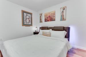 a white bedroom with a large bed and some pictures at Cozy Inwood Apartment History, Hiking and Wine! in Inwood