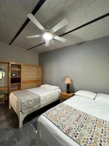 a bedroom with two beds and a ceiling fan at Mama Chuy Hotel & Villas in San Juan Cosalá