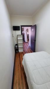 sypialnia z białym łóżkiem i drewnianą podłogą w obiekcie Hostal Magnolia w mieście Los Ángeles