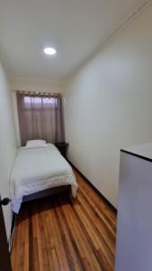 a bedroom with a bed and a wooden floor at Hostal Magnolia in Los Ángeles