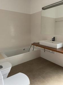 un bagno con lavandino, WC e specchio di Villa d'Es Bot a Cala Morell