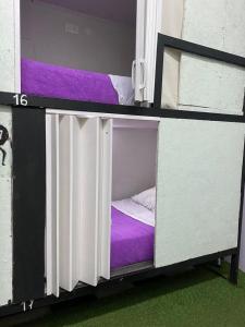 um quarto com 2 beliches com lençóis roxos em Hostel la Antigua Capsula em Cartagena de Indias