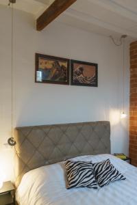 ein Bett mit zwei Bildern über der Wand in der Unterkunft CasaMancio, loft in heart of medieval Tuscan city in Pistoia