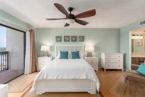 a bedroom with a white bed and a ceiling fan at Beach views with top complex amenities and covered parking! in Ormond Beach
