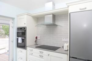 a kitchen with white cabinets and a stove top oven at Killala 1 bed cottage in Killala