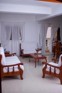 una sala de estar con muebles de madera y cortinas blancas. en Casa Ramos Castro en Mindelo