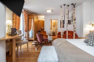 a bedroom with a bed and a desk and chairs at Hotel Folgarida in Folgarida