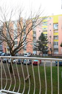 a white fence with cars parked in a parking lot at Studio apartman Dora in Vinkovci