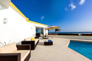 an outdoor patio with a pool and chairs and an umbrella at Lovely 4-Bed Villa in Anguilla in Long Path