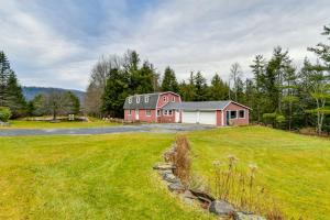 a red house on a hill with a grass field at Wooded Walton Home with Fire Pit and On-Site Pond! in Walton
