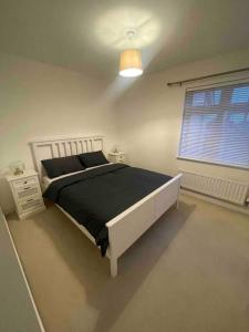 een slaapkamer met een bed met een zwarte deken en een raam bij Beautiful Modern Tranquil Two Bedroom Apartment in Swanscombe