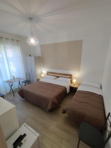 a bedroom with two beds and a desk and a table at B&B Vento Aureo Rooms in Milazzo