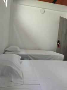 Descanso y tranquilidad في سانتا في دي أنتيوكيا: غرفة نوم بسريرين في غرفة بيضاء