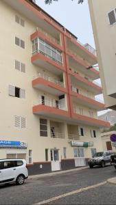 un gran edificio de apartamentos con coches aparcados frente a él en Casa Ramos Castro en Mindelo