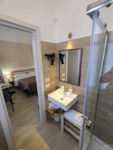 a bathroom with a sink and a mirror and a bed at B&B Vento Aureo Rooms in Milazzo