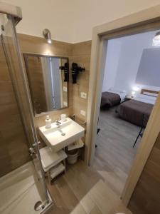 a bathroom with a sink and a mirror and a bed at B&B Vento Aureo Rooms in Milazzo