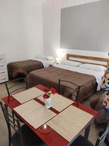 a room with two beds and a table with flowers on it at B&B Vento Aureo Rooms in Milazzo
