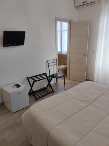 a bedroom with a bed and a chair and a television at B&B Vento Aureo Rooms in Milazzo