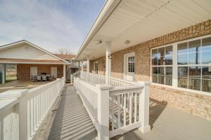 a home with a white porch and a brick building at Family Home in Vinita with Fire Pit and Game Room! in Vinita