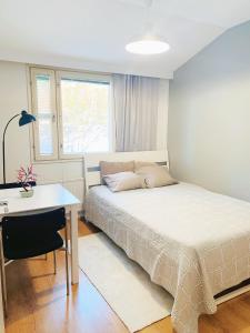 a bedroom with a bed and a desk and a window at Private rooms near metro, free parking in Helsinki