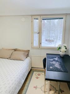 um quarto com uma cama, uma secretária e uma janela em Private rooms near metro, free parking em Helsinque