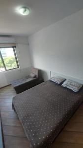 1 dormitorio con cama y sofá en Apartamento Ingleses Norte 30m da praia, en Florianópolis