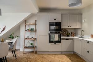 a kitchen with white cabinets and black appliances at Kist Accommodates - Hughenden Haven in Harrogate