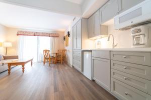een keuken met witte kasten en een woonkamer met een tafel bij Horseshoe Valley Suites - The Pine in Shanty Bay