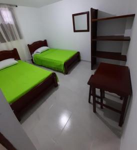 duas camas num quarto com uma mesa e uma cadeira em Hostal la Lomita em Popayan