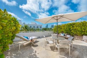 een patio met een tafel en stoelen en een parasol bij Bentley Hotel South Beach in Miami Beach