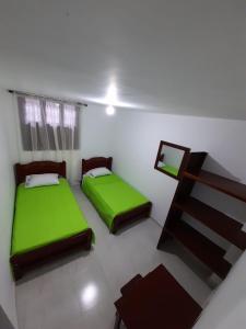 2 camas en una habitación con sábanas verdes en Hostal la Lomita, en Popayán