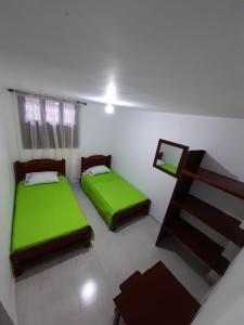 two beds in a room with green sheets at Hostal la Lomita in Popayan