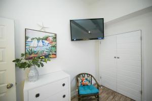 a bedroom with a tv on a white wall at Buttonwood Cottage in Anna Maria