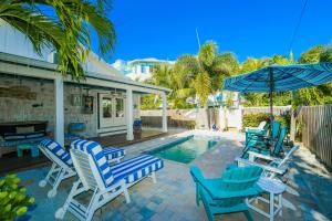 a group of chairs and an umbrella next to a swimming pool at Buttonwood Cottage in Anna Maria