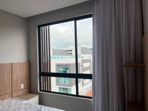 a bedroom with a window with a view of a building at Flat espaçoso e estiloso na Praia do Bessa a uma quadra do mar! in João Pessoa +85 photos