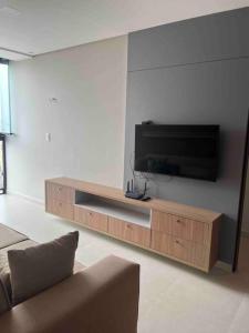 a living room with a flat screen tv on a wall at Flat espaçoso e estiloso na Praia do Bessa a uma quadra do mar! in João Pessoa