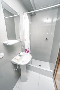 La salle de bains blanche est pourvue d'un lavabo et d'une douche. dans l'établissement Escobedo’s Inn Machupicchu, à Machu Picchu