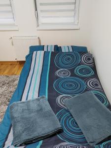 a bed in a room with a blue and gray bedspread at Apartman SM in Sremska Mitrovica