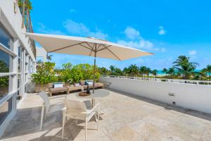 eine Terrasse mit einem Tisch, Stühlen und einem Sonnenschirm in der Unterkunft Bentley Hotel South Beach in Miami Beach