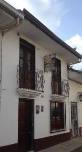 un edificio bianco con due balconi e un cartello sopra di Hostal la Lomita a Popayan