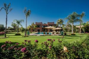 a house with a yard with a pool and palm trees at La Villa Rose Anna in Marrakesh