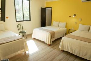 a hotel room with two beds and a chair at Casa Janaab Palenque in Palenque +40 photos