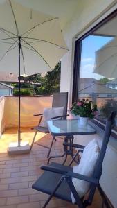 un patio con mesa, sillas y sombrilla en Ankommen und wohlfühlen 2 en Bad Bergzabern