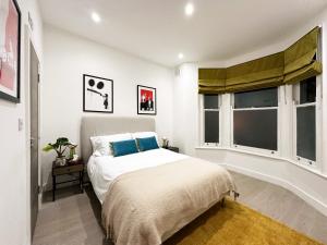 a bedroom with a bed and two windows at Nancys Place in Notting Hill hosted by AirOperate in London