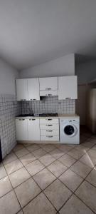 a kitchen with white cabinets and a washing machine at Casa Minuredda in Olbia