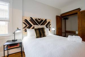 Schlafzimmer mit einem großen weißen Bett mit einem Kopfteil aus Holz in der Unterkunft Notorious Outlaw in Denver