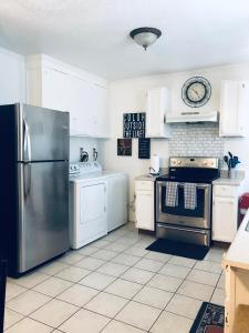 uma cozinha com armários brancos e um frigorífico de aço inoxidável em Cozy 2 bedroom 1 bath unit em Anderson