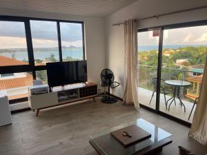 a living room with a tv and large windows at Hotel Kenito Apartamentos T1 To T3 in São Tomé
