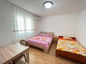 Duas camas num pequeno quarto com uma mesa e uma mesa em Aniva Apartments em Šušanj