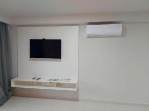 um quarto branco com uma televisão na parede em Flat Frente Mar - Praia de Tabatinga em Conde